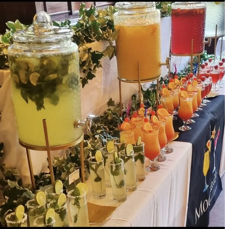 Colorful juice and refreshment dispensers with neatly arranged glasses